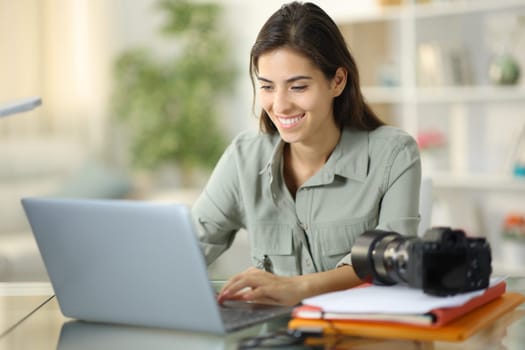 Happy photographer checking result on laptop at home