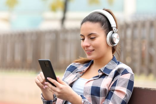 Happy teen listening music in a bench