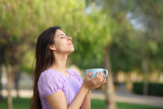 Profile of a woman breathing drinking coffee in a green park