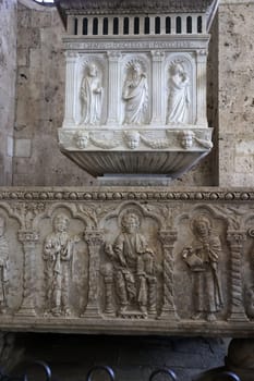 Massa Marittima, Italy - Sept 11, 2022:  Monumental baptismal font, with a rectangular bath surmounted by a small temple. The baptistery dates from 1267. Cathedral of Saint Cerbonius in Massa Marittima. Italy
