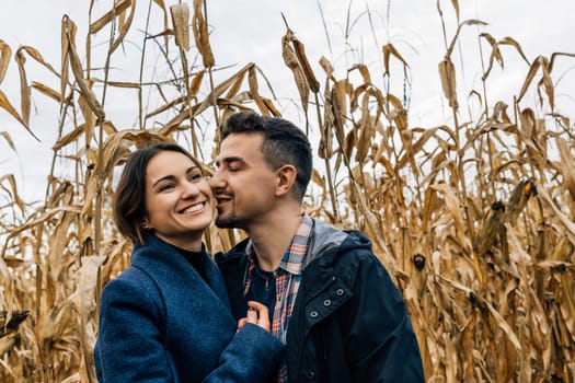 Moments of tenderness of a happy couple in love on a walk outside the city in autumn among a cornfield.