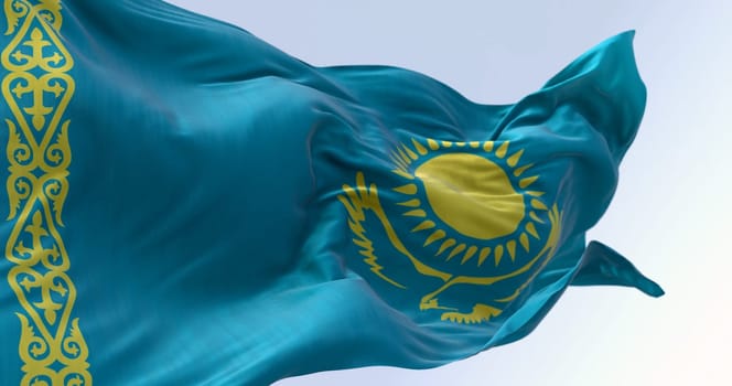 Close-up of Kazakhstan national flag waving on a clear day. Light blue field with a yellow sun and flying eagle in the center and a yellow ornamental band. 3d illustration render. Rippling fabric