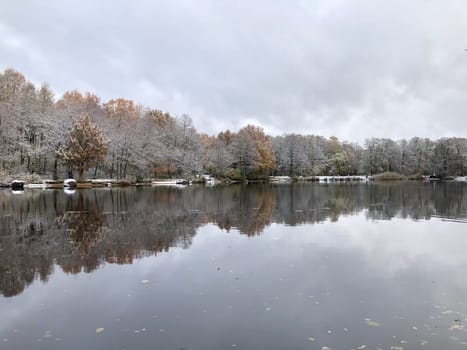 trees covered with snow and frost, as if silver, are reflected in the smooth mirror water of the river, winter landscape