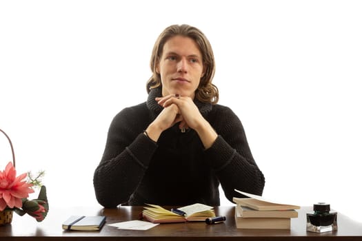 A student sits at a table and write a notebook on a white background