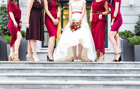 Bride with bridesmaids on the park on the wedding day.