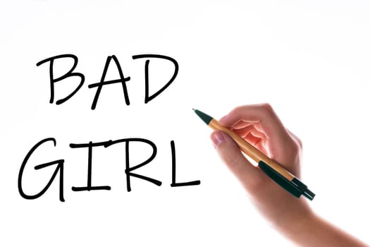 Children hand with pen write on a blue white background. Writing hand. Words Bad girl