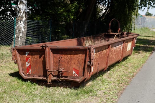 Old brown dumpster with plant waste standing on a meadow, Germany, Europe