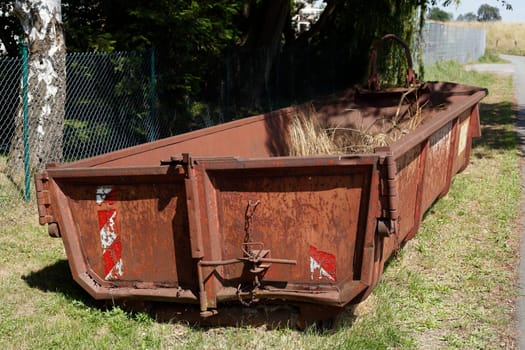Old brown dumpster with plant waste standing on a meadow, Germany, Europe