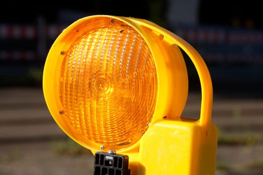 Orange construction site lamp on a construction site barrier, Germany