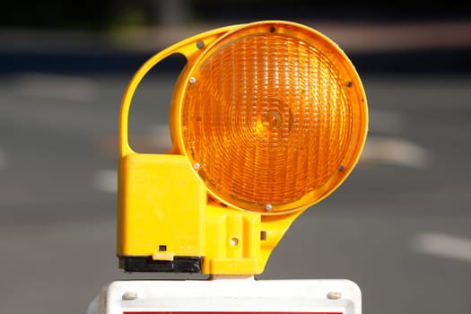 Orange construction site lamp on a construction site barrier, Germany
