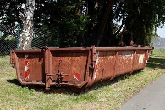 Old brown dumpster with plant waste standing on a meadow, Germany, Europe