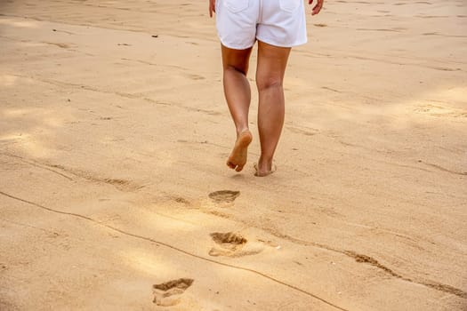 Woman walking on the sand at the beach.