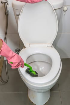 Woman cleaning toilet ware that is very dirty.