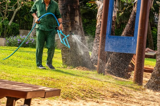 A man uses a hose to water the lawn.