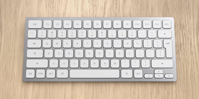Modern wireless aluminum computer keyboard with white keys on wooden desk