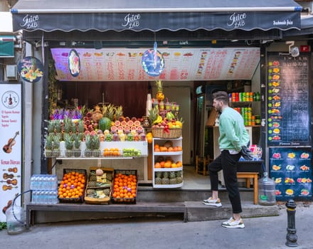 Istanbul, Turkey - May 13, 2023: Bustling fruit stand and juice bar overflowing with fresh fruits, including oranges, pomegranate, pineapples, watermelons, grapefruits, and bananas in Istiklal street