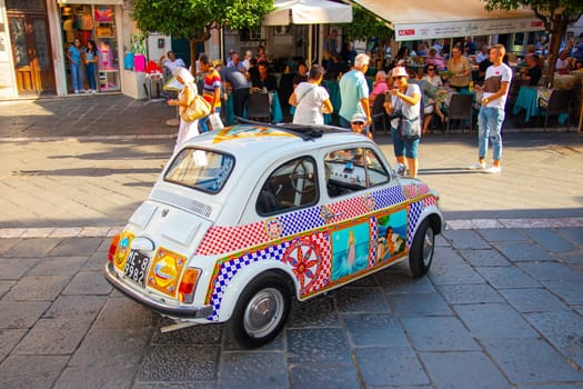 Taormina, Sicily, Italy - 28 September 2023: A vintage Fiat 500 vehicle beautifully decorated with Sicilian pictorial elements in the pedestrian zone of Taormina.