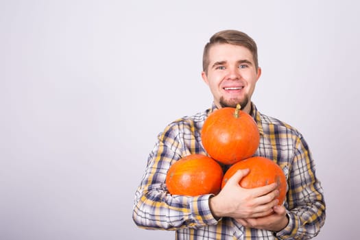 portrait of a young farmer holding a pumpkins on a light background studio.