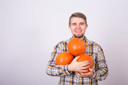 portrait of a young farmer holding a pumpkins on a light background studio.
