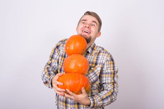 portrait of a young farmer holding a pumpkins on a light background studio.