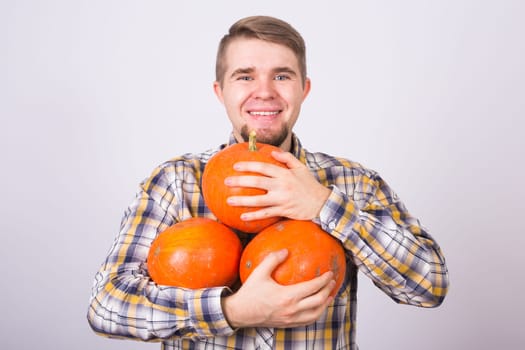 portrait of a young farmer holding a pumpkins on a light background studio.
