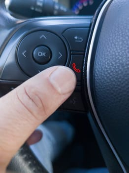 Driver about to hang up the phone from the steering wheel controls. Using a phone while driving