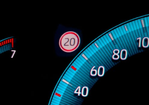 Speed limit warning close to speedometer indicator. Digital car dashboard closeup