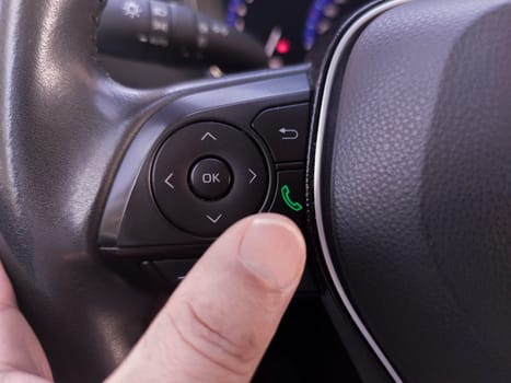 Driver about to pick up the phone from the steering wheel controls