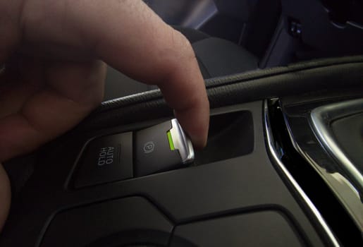 Driver pulling the electric parking brake of his car. Green color light indicating brake activation