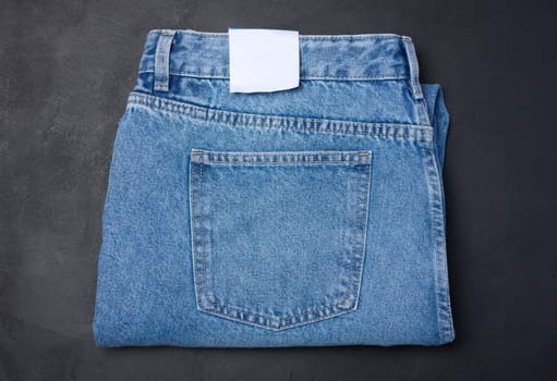Folded blue jeans on a black background, top view