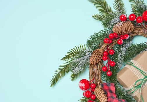 Christmas wreath made of fir branches and other decorations on a blue background, copy space