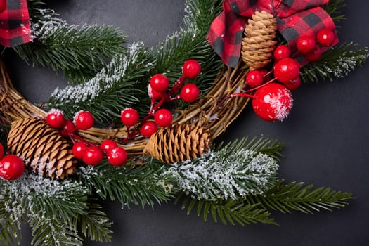 A circular Christmas wreath made of fir branches and other decorations on a black chalkboard