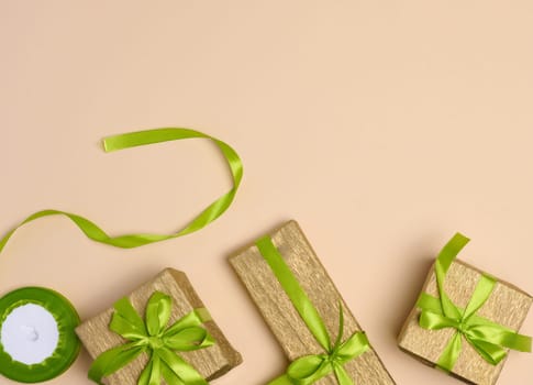 Boxes packed in yellow paper and tied with ribbon on a beige background, gifts