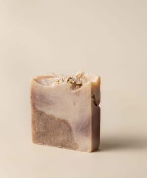 Natural herbal brown handmade soap bar on light beige close up. Hygiene product for Spa and skin care. Using organic handmade sopas in everyday routine