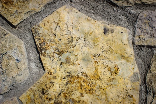 The texture of coarse old, ancient brown carved uneven stones, cobblestones with the suture laid on the floor in the bristchatku. The background.