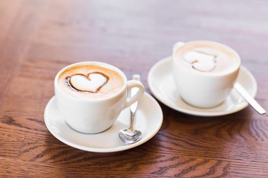 Two cups of coffee with heart pattern.