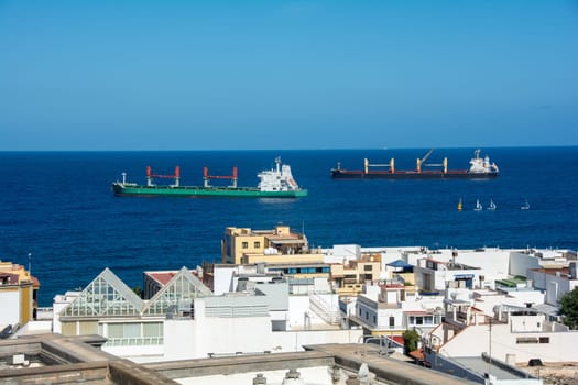 Freighter in the sea with roofs of the city of Las Palmas Gran Canaria, Spain in the foreground