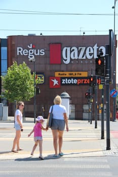 Family crosses street in city. City life. Street in Lodz city. Cityscape. Urban panorama. Mother with children crossing the street