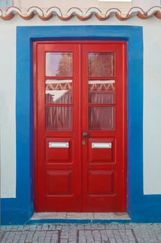 Tiny door painted with vivid colors at Vila Nova de Milfontes house. Little picturesque town on the Alentejo coast, Portugal