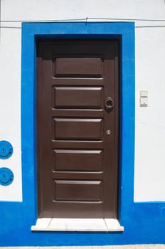Tiny door painted with vivid colors at Vila Nova de Milfontes house. Little picturesque town on the Alentejo coast, Portugal