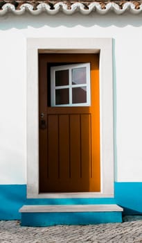 Tiny door painted with vivid colors at Vila Nova de Milfontes house. Little picturesque town on the Alentejo coast, Portugal