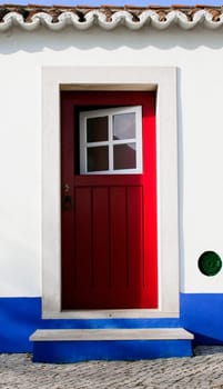 Tiny door painted with vivid colors at Vila Nova de Milfontes house. Little picturesque town on the Alentejo coast, Portugal