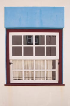 Tiny window painted with vivid colors at Vila Nova de Milfontes house. Little picturesque town on the Alentejo coast, Portugal