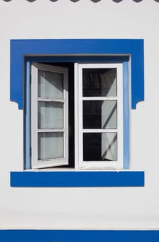 Tiny window painted with vivid colors at Vila Nova de Milfontes house. Little picturesque town on the Alentejo coast, Portugal