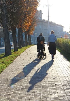 family with stroller walking through the autumn park. Walking with infant in open air. Newborn, family, child, parenthood. Modern family walking along street with stroller. Walk around the city