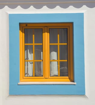Tiny window painted with vivid colors at Vila Nova de Milfontes house. Little picturesque town on the Alentejo coast, Portugal