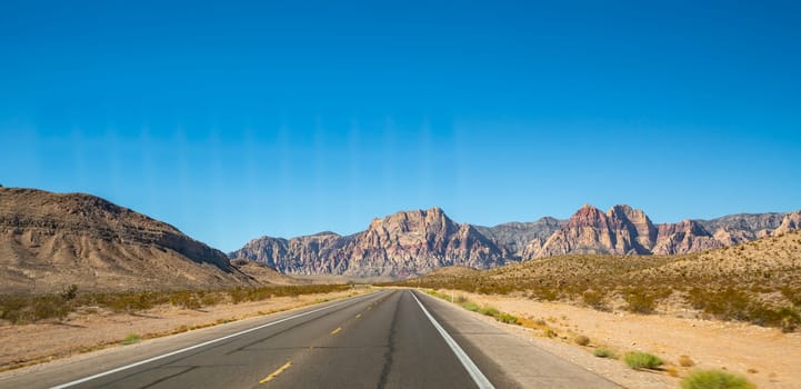 Empty long nevada mountain road to the horizon on a sunny summer day at bright sunset
