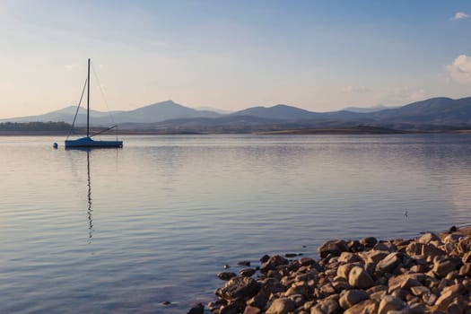 Sailing boat anchored on the shore of the Gabriel y Galan reservoir, Caceres, Spain. Active tourism at freshwaters coasts concept