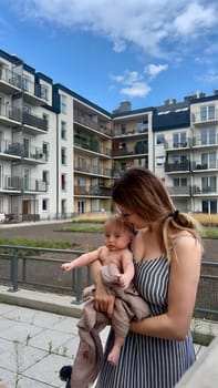 A young woman with a baby in her arms rests on the terrace.