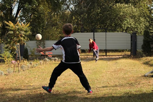 Two boys friends are playing ball in the backyard on summer vacation